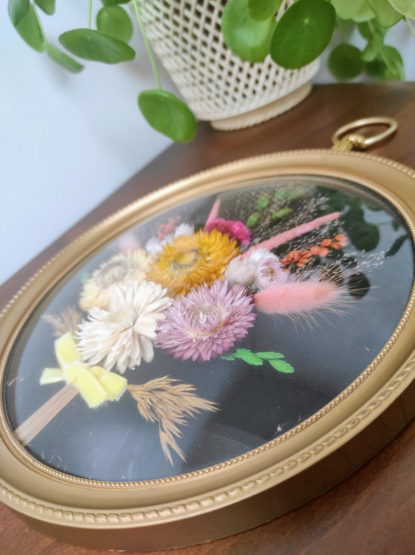 Beau cadre vintage de forme ronde avec fleurs naturelles séchées en bouquet. Le verre est bordé d’un cadre doré. Une attache est présente au dos. De belles couleurs automnales et beaucoup de charme pour ce beau cadre.