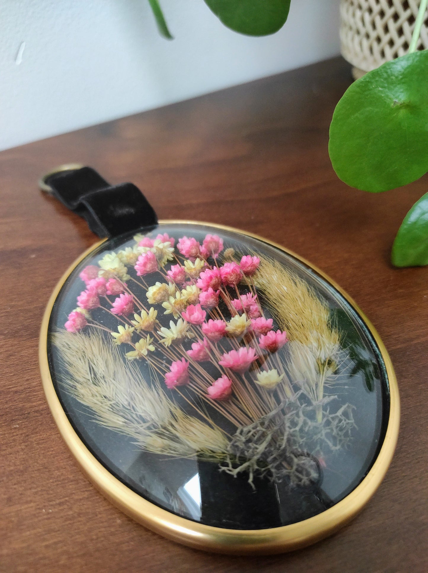 Beau petit cadre vintage de forme ovale avec fleurs naturelles séchées en bouquet. Le verre bombé est bordé d’un liseré doré. Une attache en velours est présente. De belles couleurs et beaucoup de charme pour ce beau petit cadre.