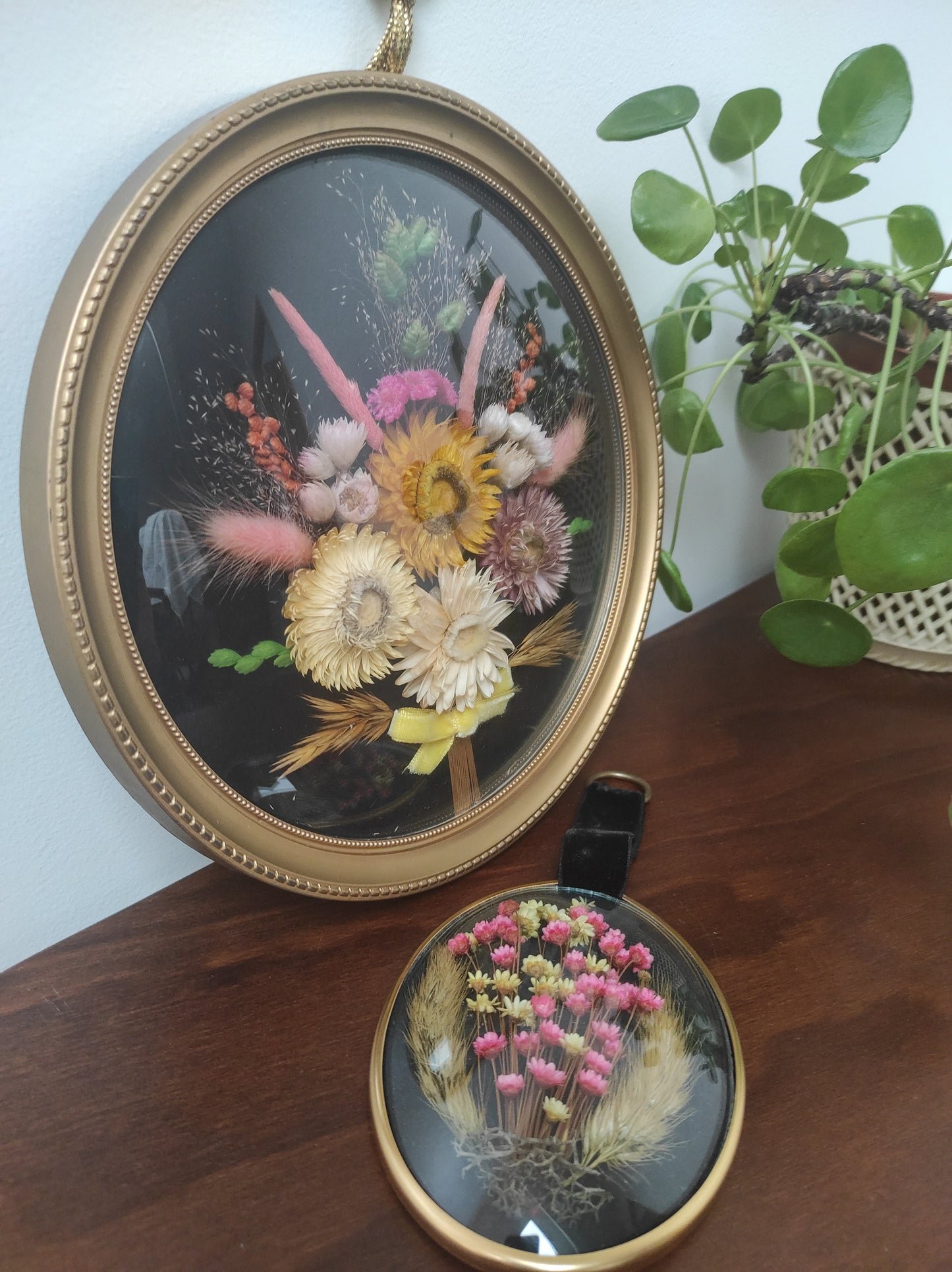 Beau cadre vintage de forme ronde avec fleurs naturelles séchées en bouquet. Le verre est bordé d’un cadre doré. Une attache est présente au dos. De belles couleurs automnales et beaucoup de charme pour ce beau cadre.