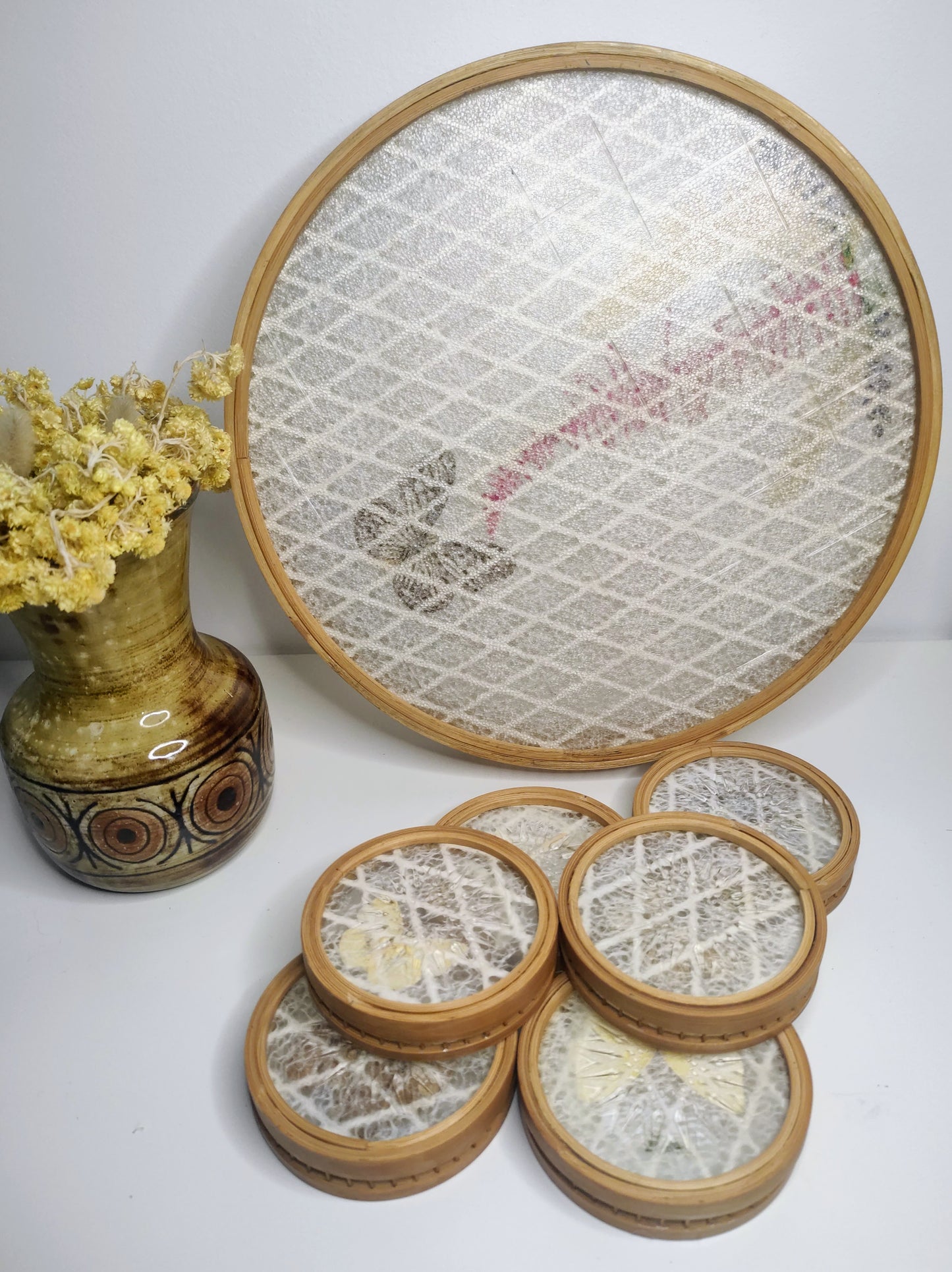 Un apéritif de prévu… Faites voyager vos convives avec ce set apéritif en rotin des années 70 composé de 6 dessous de verres papillons et leur plateau. Les sous-verres ainsi que le plateau sont en bois et composés de véritables ailes de différents papillons (corps en papier). En très bon état. Service vintage