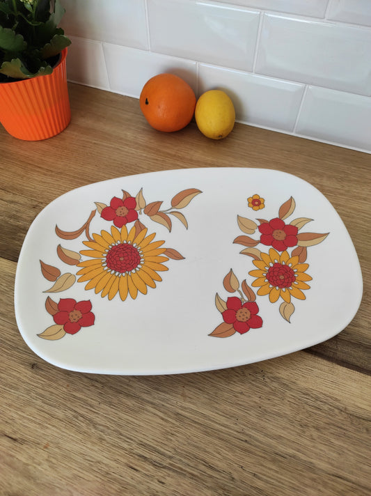 Grand plat de service en mélamine CAROLINE années 70. Ancien grand plat de service en mélamine vintage. Avec son décor floral jaune et orange typique des années 70, ce plat sera parfait aussi bien pour votre pique-nique, vos vacances au camping ou simplement sur votre table ! Made in France, en très bon état. Vintage, kitsch