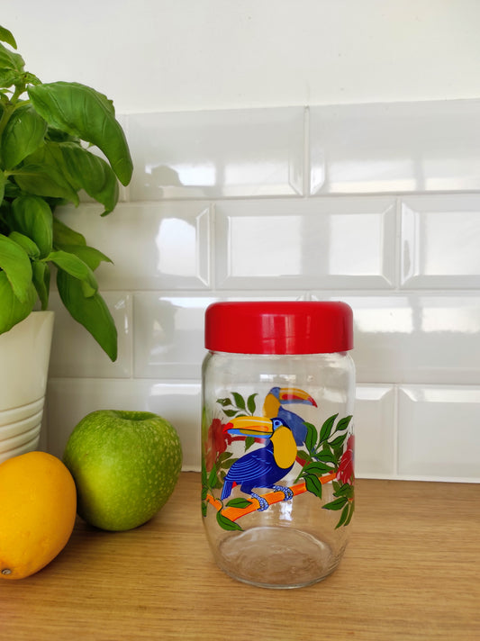 Pot de conservation à décor toucan LE PARFAIT. Pot de conservation, bocal en verre coloré Le Parfait motifs toucan et fleurs d'hibiscus des années 70. Avec son bouchon à vis rouge, ce bocal vintage de la marque LE PARFAIT sera votre allié pour une maison zéro déchet pour stocker pâtes, riz, épices en cuisine.