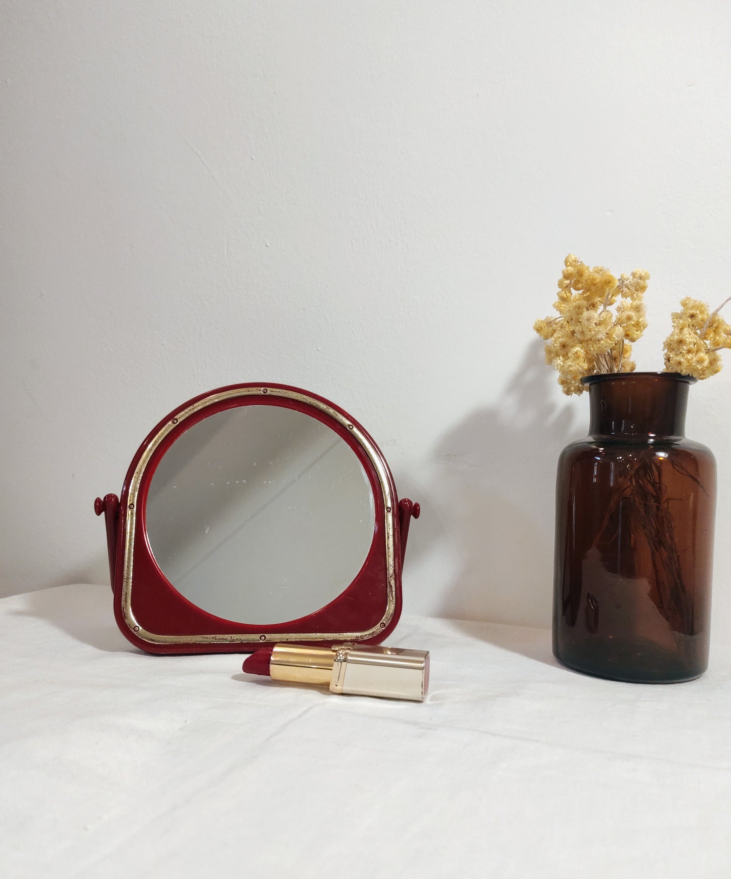 Miroir à poser en plastique rouge vintage. Ancien petit miroir à poser en plastique rouge et liseré doré des années 70/80. A noter : des traces du temps, léger coup sur le plastique en haut du miroir (voir photo) Dimensions : 15 cm x 15 cm Poids : 190 gr