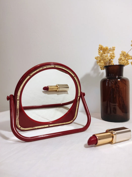 Miroir à poser en plastique rouge vintage. Ancien petit miroir à poser en plastique rouge et liseré doré des années 70/80. A noter : des traces du temps, léger coup sur le plastique en haut du miroir (voir photo) Dimensions : 15 cm x 15 cm Poids : 190 gr