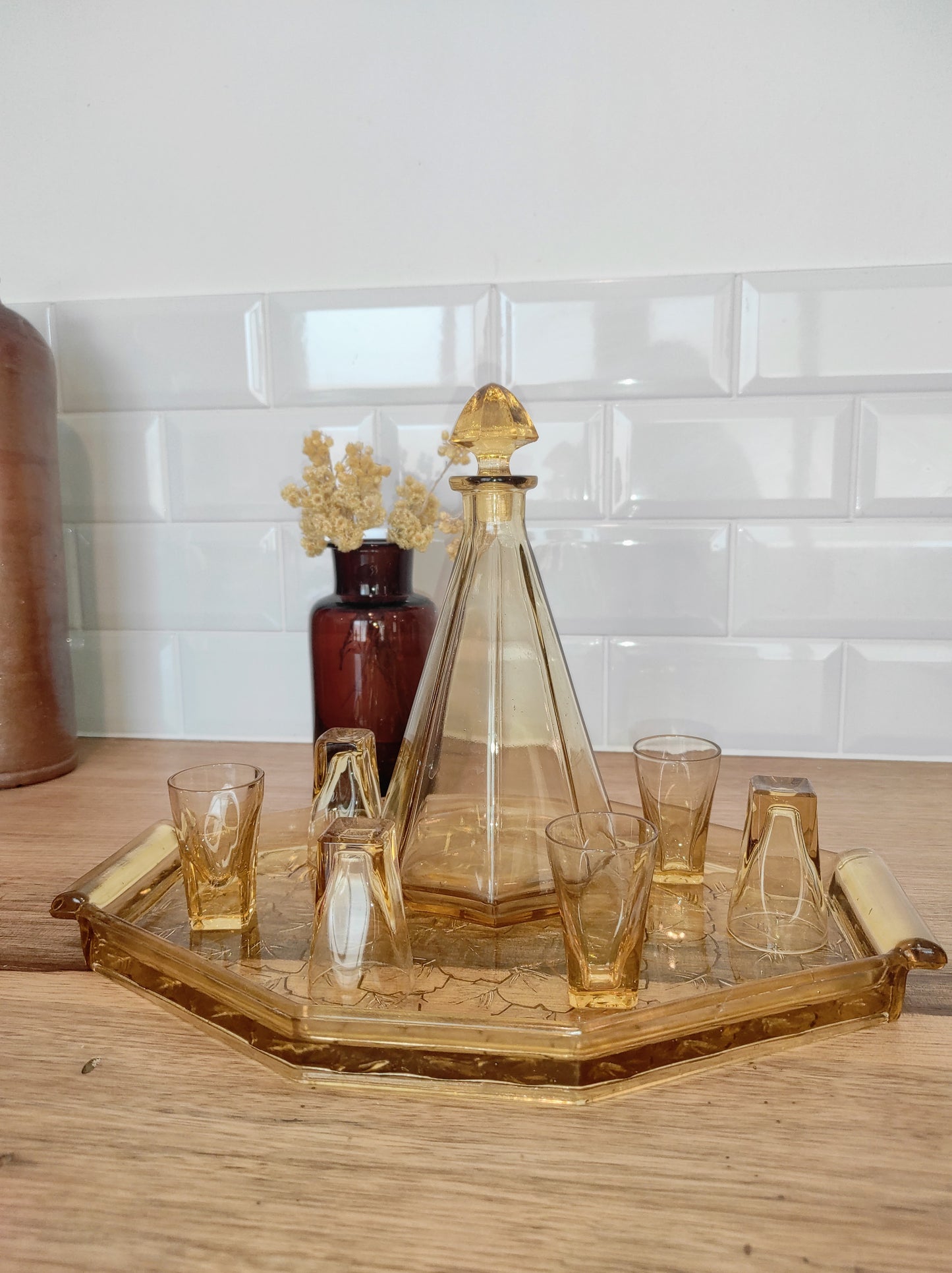Ancien service à liqueur art déco jaune année 50. Ancien service à liqueur art déco en verre jaune comprenant 6 verres, une carafe et un plateau assez lourd aux motifs feuilles de vigne. Le service est en très bon état.