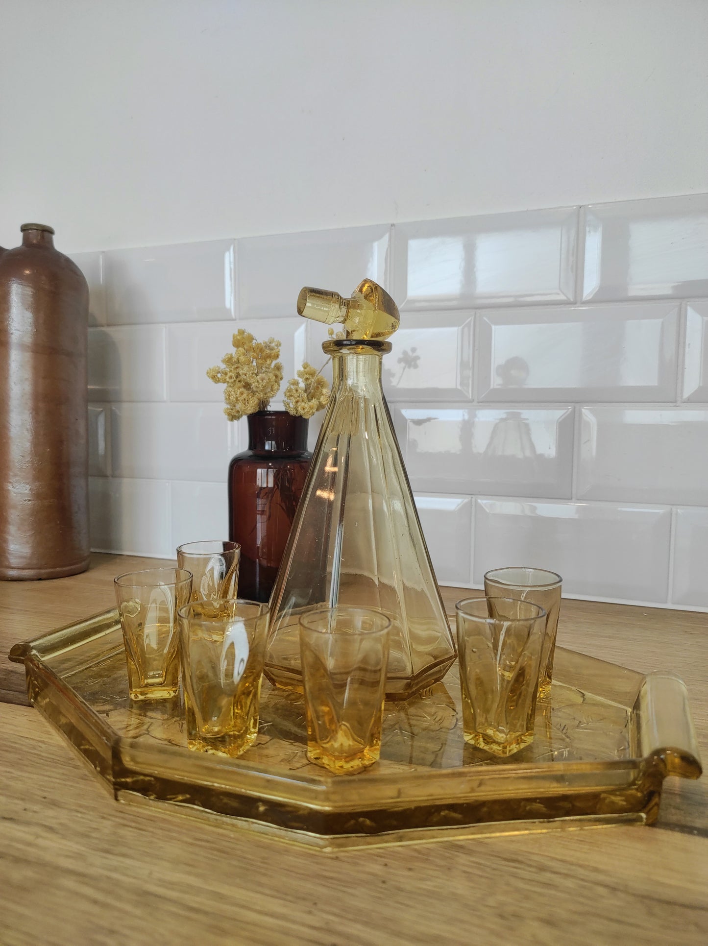 Ancien service à liqueur art déco jaune année 50. Ancien service à liqueur art déco en verre jaune comprenant 6 verres, une carafe et un plateau assez lourd aux motifs feuilles de vigne. Le service est en très bon état.