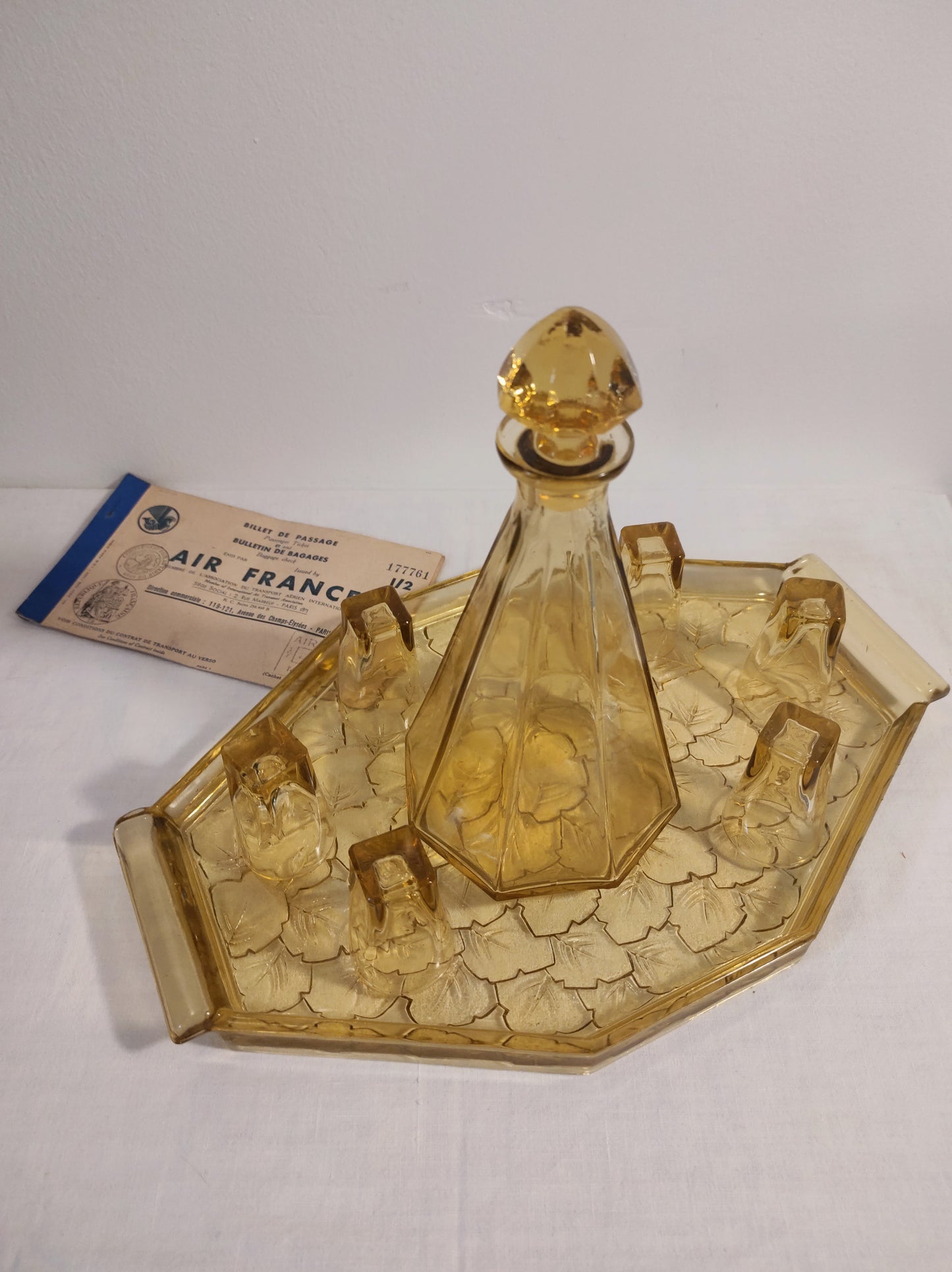 Ancien service à liqueur art déco jaune année 50. Ancien service à liqueur art déco en verre jaune comprenant 6 verres, une carafe et un plateau assez lourd aux motifs feuilles de vigne. Le service est en très bon état.