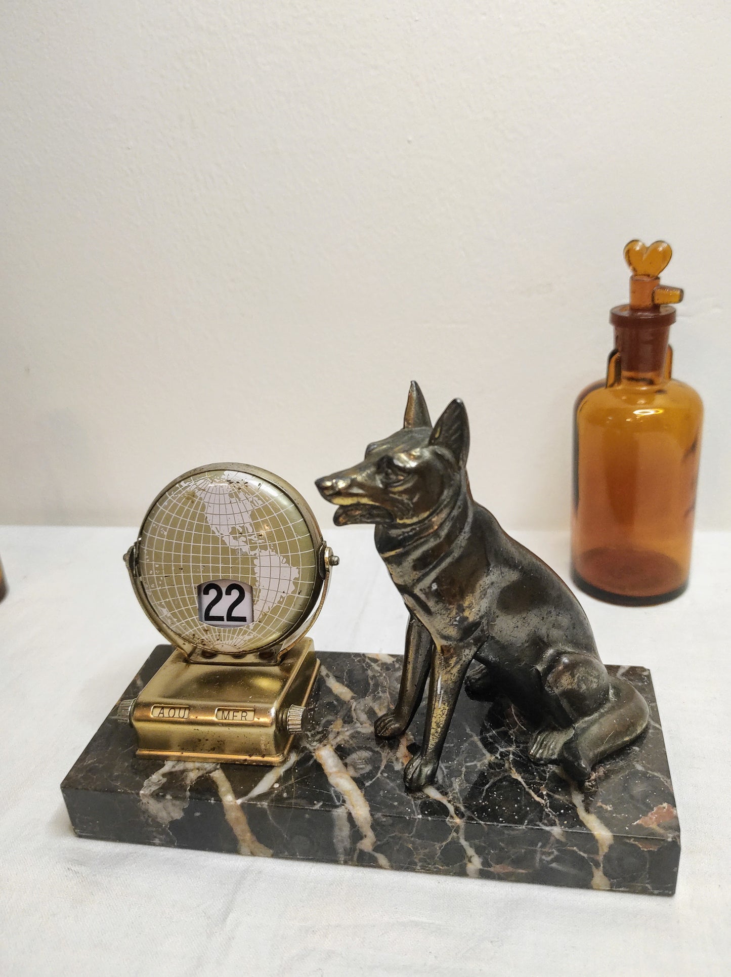 Ancien calendrier perpétuel en marbre et régule. Attention Rex monte la garde et surveille la date du jour ! Avec cet ancien calendrier perpétuel en régule monté sur un marbre gris foncé et blanc qui donnera un air vintage à votre bureau vous ne changerais plus de calendrier tous les ans ! Malgré des traces du temps il est en très bon état. Calendrier vintage