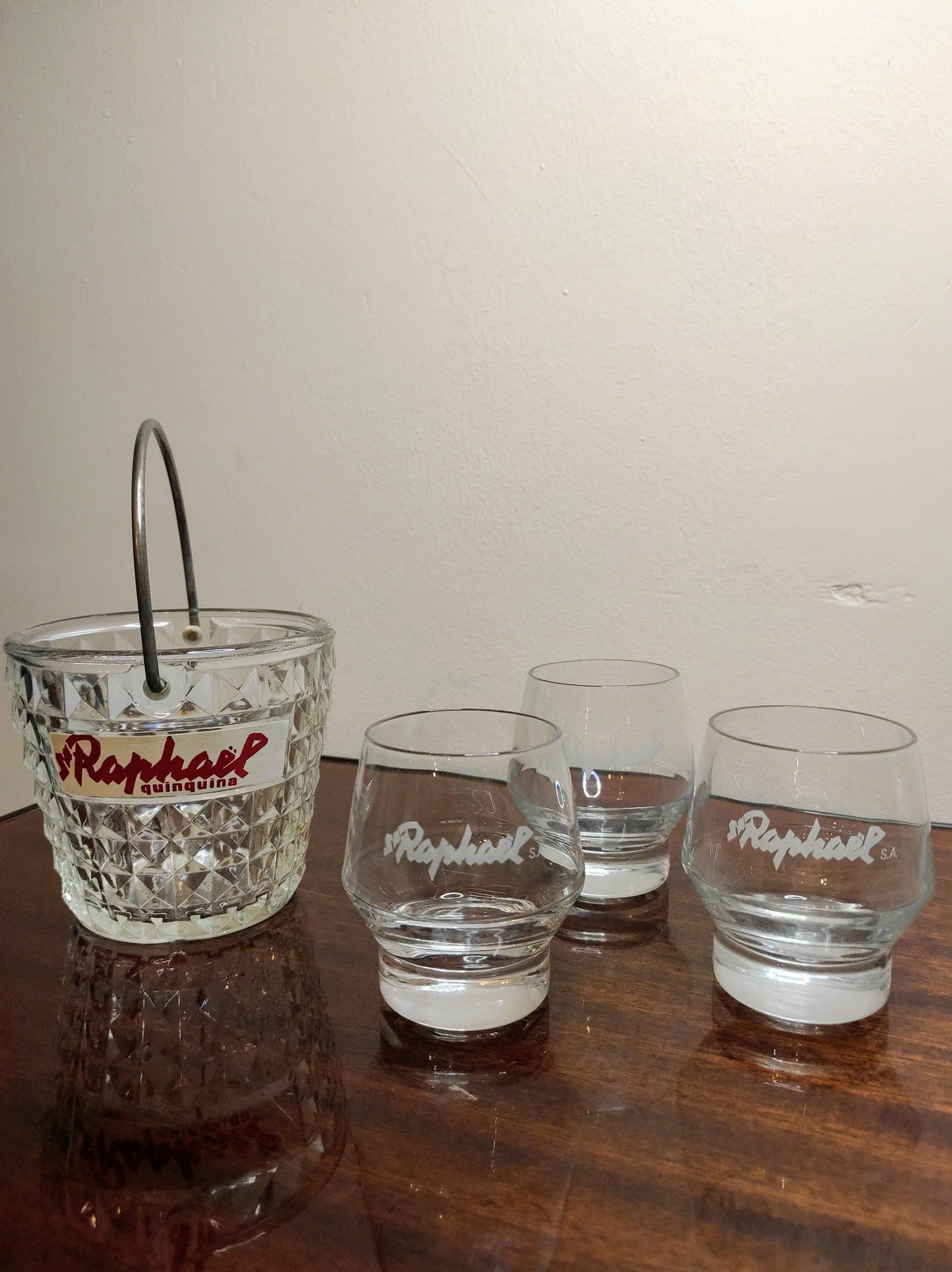 Ancien sceau à glaçons St Raphaël quinquina et ses 3 verres vintage. Pour les fortes chaleurs de l'été n'oubliez pas de rajouter des glaçons dans votre verre ! Ancien sceau à glace en verre moulé St Raphaël quinquina accompagné de 3 verres à liqueur St Raphaël. Made in France, le tout en très bon état.