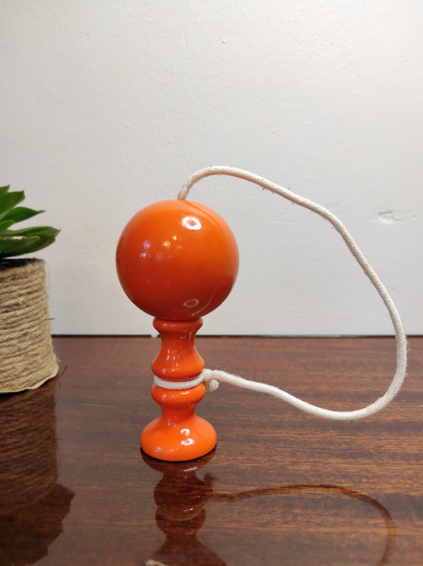 Ancien petit bilboquet en bois orange vintage. Ce joli jouet ancien sera parfait en déco sur une étagère ou dans la chambre de votre bambin ! A noter : en très bon état