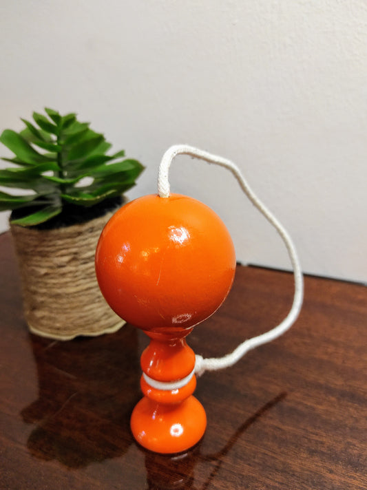 Ancien petit bilboquet en bois orange vintage. Ce joli jouet ancien sera parfait en déco sur une étagère ou dans la chambre de votre bambin ! A noter : en très bon état