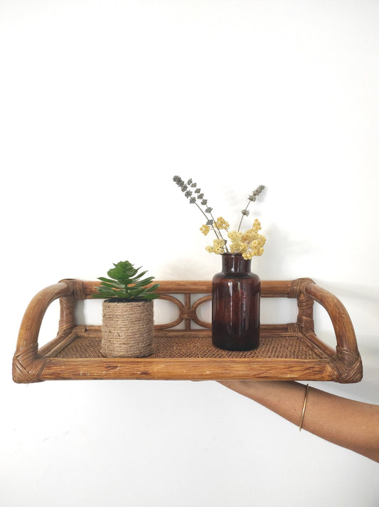 Jolie étagère murale en rotin vintage. Cette ancienne étagère murale en rotin trouvera sa place dans votre intérieur. Son format est idéal pour s'adapter à toutes les pièces de la maison, et accueillir livres ou déco. A noter : Dans son jus, le vernis est un peu passé à certains endroits mais reste en très bon état.