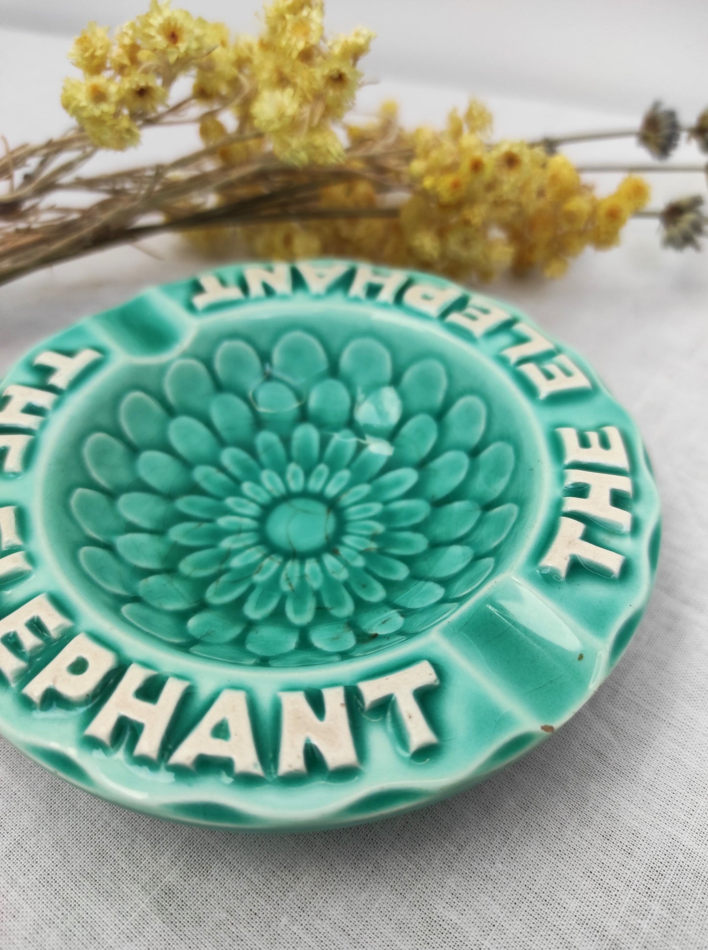 Ancien petit cendrier publicitaire Thé Éléphant. Joli petit cendrier publicitaire vintage pour la marque "Thé Elephant" en faïence de couleur bleu céladon. Le fond à des motifs en forme de pétales. Il fera une superbe déco rétro et colorée sur une étagère ou un joli vide poche sur une commode !