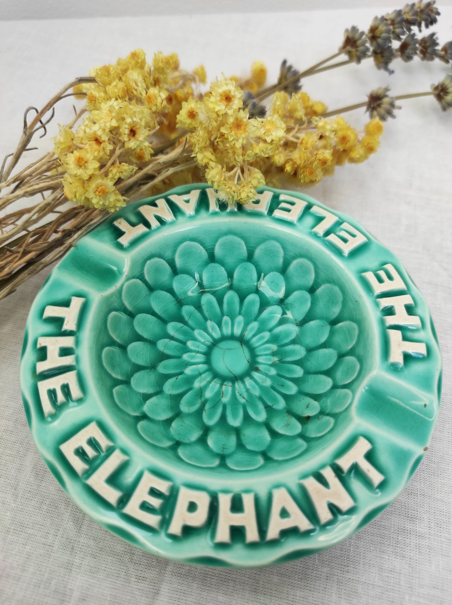 Ancien petit cendrier publicitaire Thé Éléphant. Joli petit cendrier publicitaire vintage pour la marque "Thé Elephant" en faïence de couleur bleu céladon. Le fond à des motifs en forme de pétales. Il fera une superbe déco rétro et colorée sur une étagère ou un joli vide poche sur une commode !