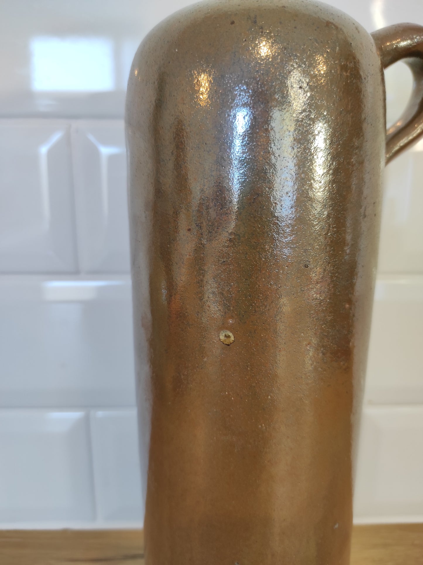 Ancienne bouteille en grès vernissé. Jolie bouteille ancienne en grès vernissé avec anse. Sa forme élancée est très décorative et accueillera à merveille vos fleurs séchées. En déco, elle fera aussi faire son effet en accumulation avec d’autres formats ou d'autres couleurs. A noter : la bouteille ayant était faite artisanalement, elle porte quelques petits défauts qui n'enlèvent rien à son charme. Aucun éclat.