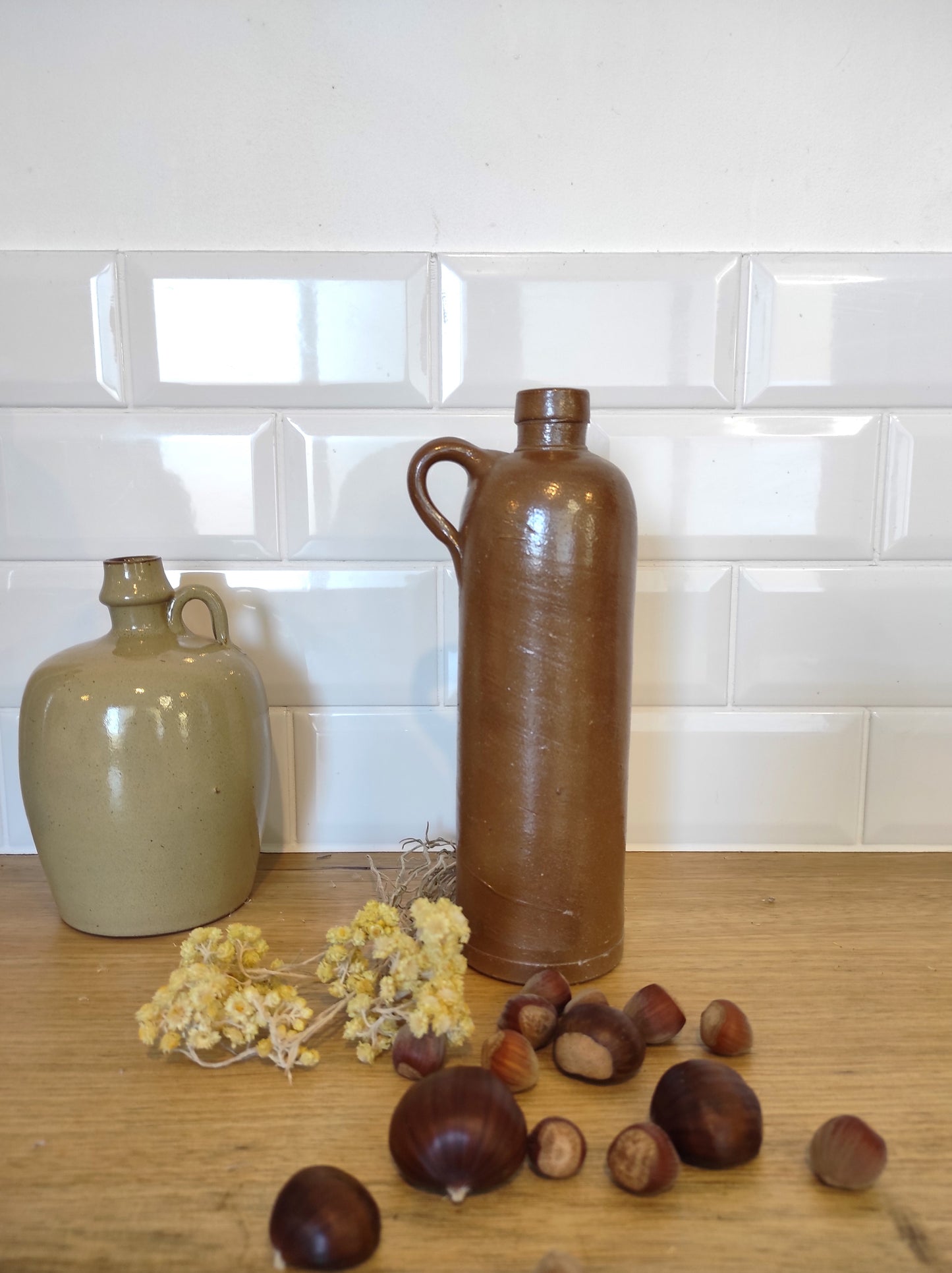Ancienne bouteille en grès vernissé 23 cm. Jolie bouteille ancienne en grès vernissé avec anse. Un peu plus petite que sa grande sœur elle reste tout de même très décorative et accueillera à merveille vos fleurs séchées. En déco, elle fera aussi faire son effet en accumulation avec d’autres formats ou d'autres couleurs. Bouteille vintage