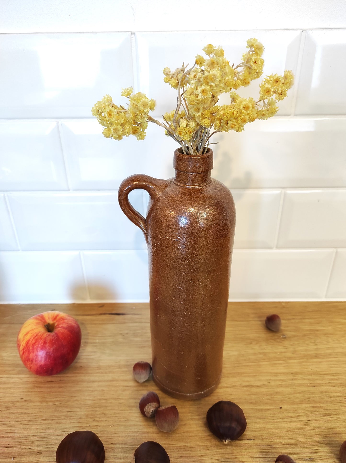 Ancienne bouteille en grès vernissé 23 cm. Jolie bouteille ancienne en grès vernissé avec anse. Un peu plus petite que sa grande sœur elle reste tout de même très décorative et accueillera à merveille vos fleurs séchées. En déco, elle fera aussi faire son effet en accumulation avec d’autres formats ou d'autres couleurs. Bouteille vintage