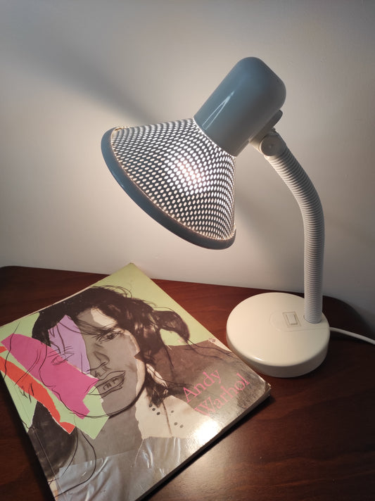 Lampe de bureau blanche des années 80. Ancienne lampe de bureau, lampe à poser en aluminium blanc des années 80 son abat-jour ajouré est orientable (haut/bas) et son interrupteur est sur le pied. Electrification d'origine vérifiée, en bon état, ampoule vis.