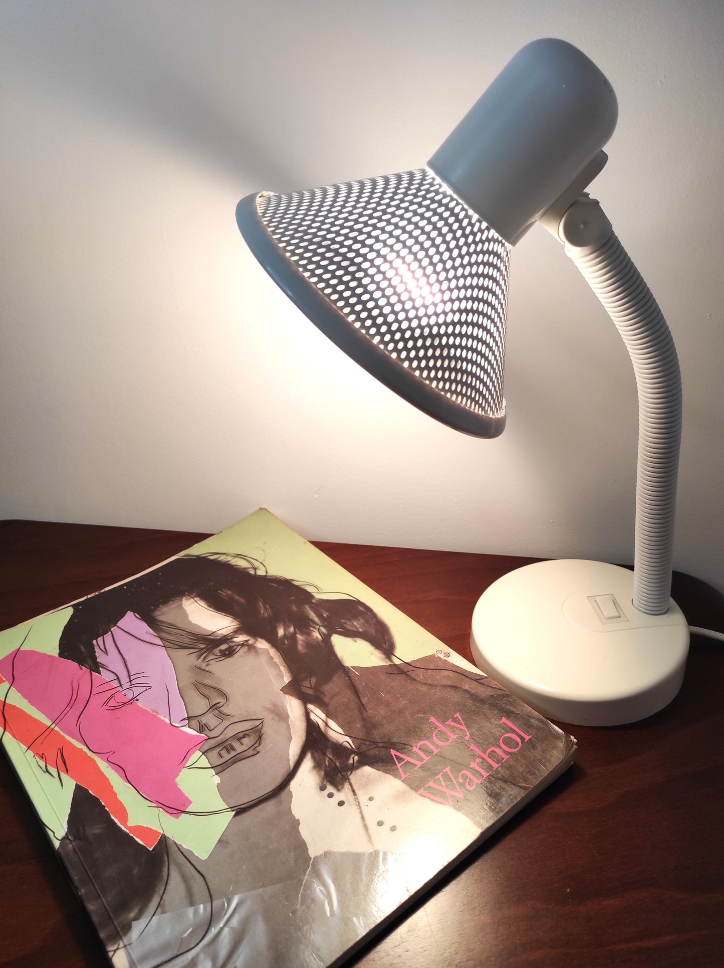 Lampe de bureau blanche des années 80. Ancienne lampe de bureau, lampe à poser en aluminium blanc des années 80 son abat-jour ajouré est orientable (haut/bas) et son interrupteur est sur le pied. Electrification d'origine vérifiée, en bon état, ampoule vis.