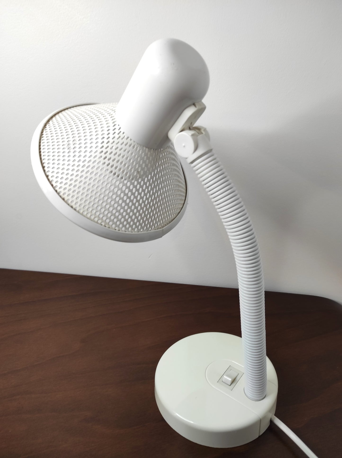 Lampe de bureau blanche des années 80. Ancienne lampe de bureau, lampe à poser en aluminium blanc des années 80 son abat-jour ajouré est orientable (haut/bas) et son interrupteur est sur le pied. Electrification d'origine vérifiée, en bon état, ampoule vis.