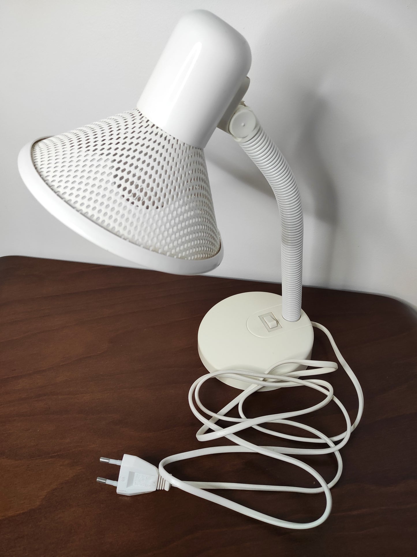 Lampe de bureau blanche des années 80. Ancienne lampe de bureau, lampe à poser en aluminium blanc des années 80 son abat-jour ajouré est orientable (haut/bas) et son interrupteur est sur le pied. Electrification d'origine vérifiée, en bon état, ampoule vis.