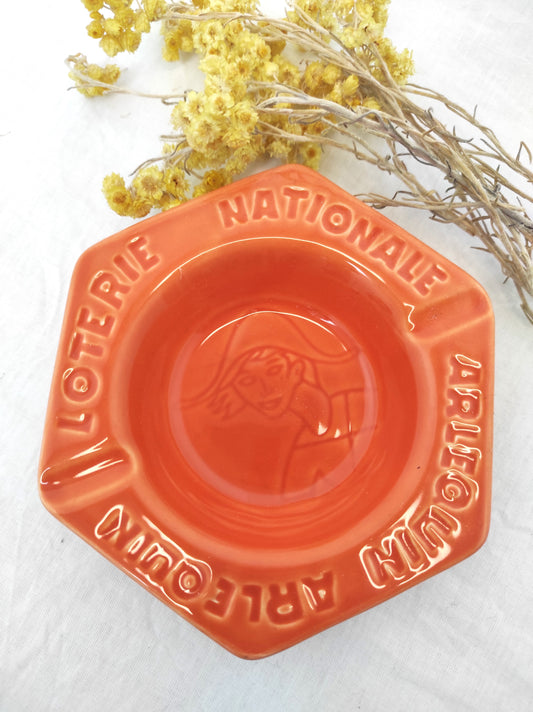 Ancien cendrier publicitaire LOTERIE NATIONALE ARLEQUIN. Joli petit cendrier publicitaire vintage Loterie Nationale Arlequin en faïence de couleur orange saumon en très bon état (aucun éclat). Il fera une superbe déco rétro et colorée sur une étagère ou un joli vide poche sur une commode ! Décoration vintage