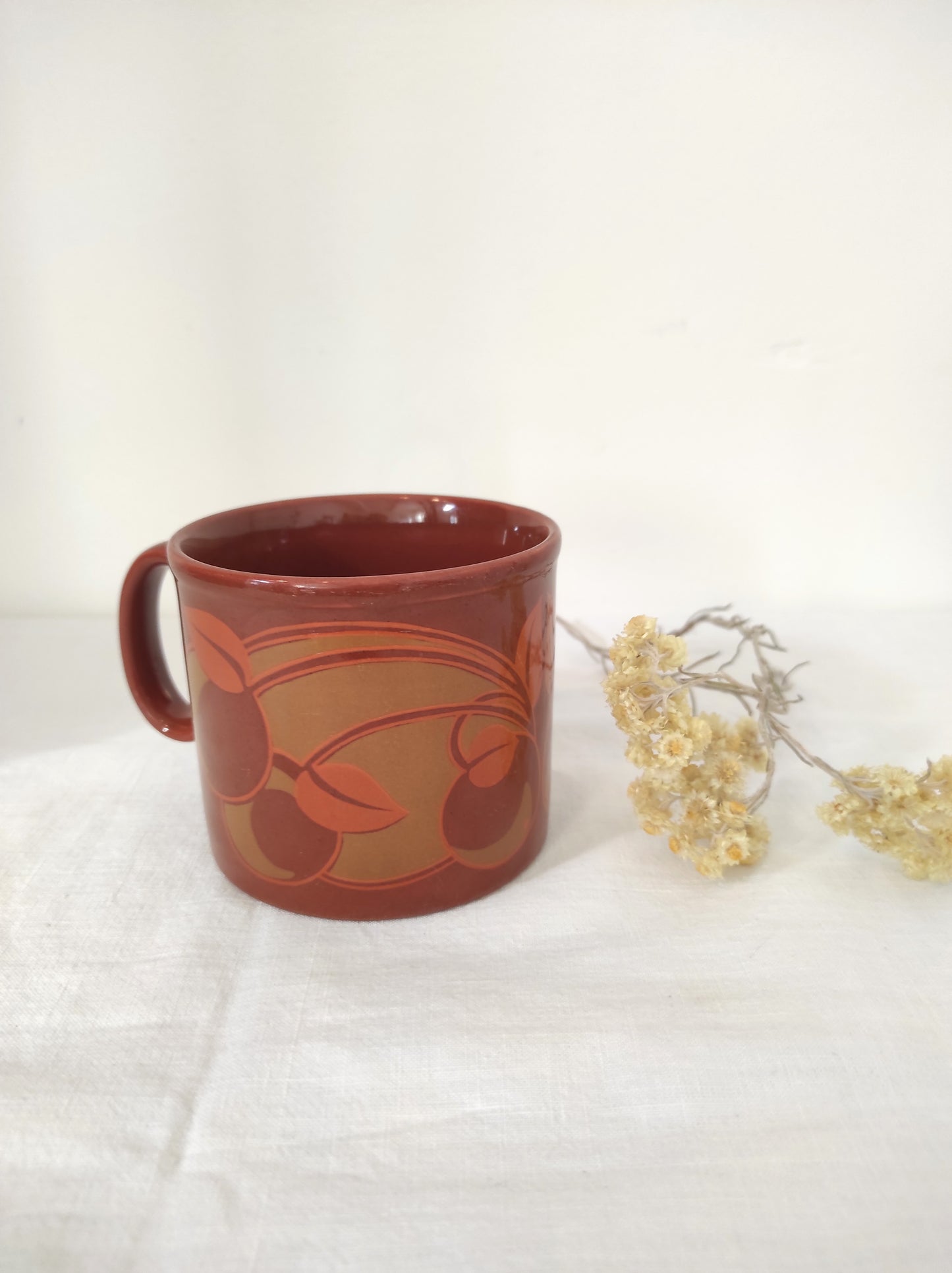 Mug vintage Klin Craft à fleurs. Pour les longues soirées d'hiver, ce mug en céramique marron et fleurs vertes et oranges de Kiln Craft Made in England sera votre parfait allié.  Aucun éclat, en très bon état. 