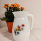 Pichet Arcopal motifs fleurs années 60. Ce joli pichet vintage en arcopal blanc avec ses petites fleurs sera élément parfait sur votre table pour un esprit vintage ou champêtre.   Sans aucun éclat, en parfait état. 