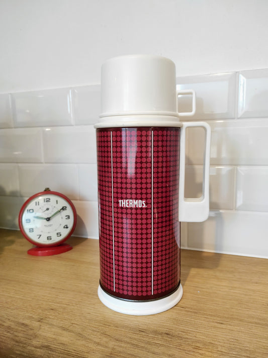 Bouteille isotherme THERMOS vintage made in England années 70. Faites vous remarquer en emportant votre café dans ce superbe thermos à pois des années 70 !  Bouteille isotherme chaud-froid de la célèbre marque THERMOS.  Corps en métal rouge foncé avec des petits pois rouges clairs.  Bouchon et gobelet/tasse en plastique.  Contenance 1 L.