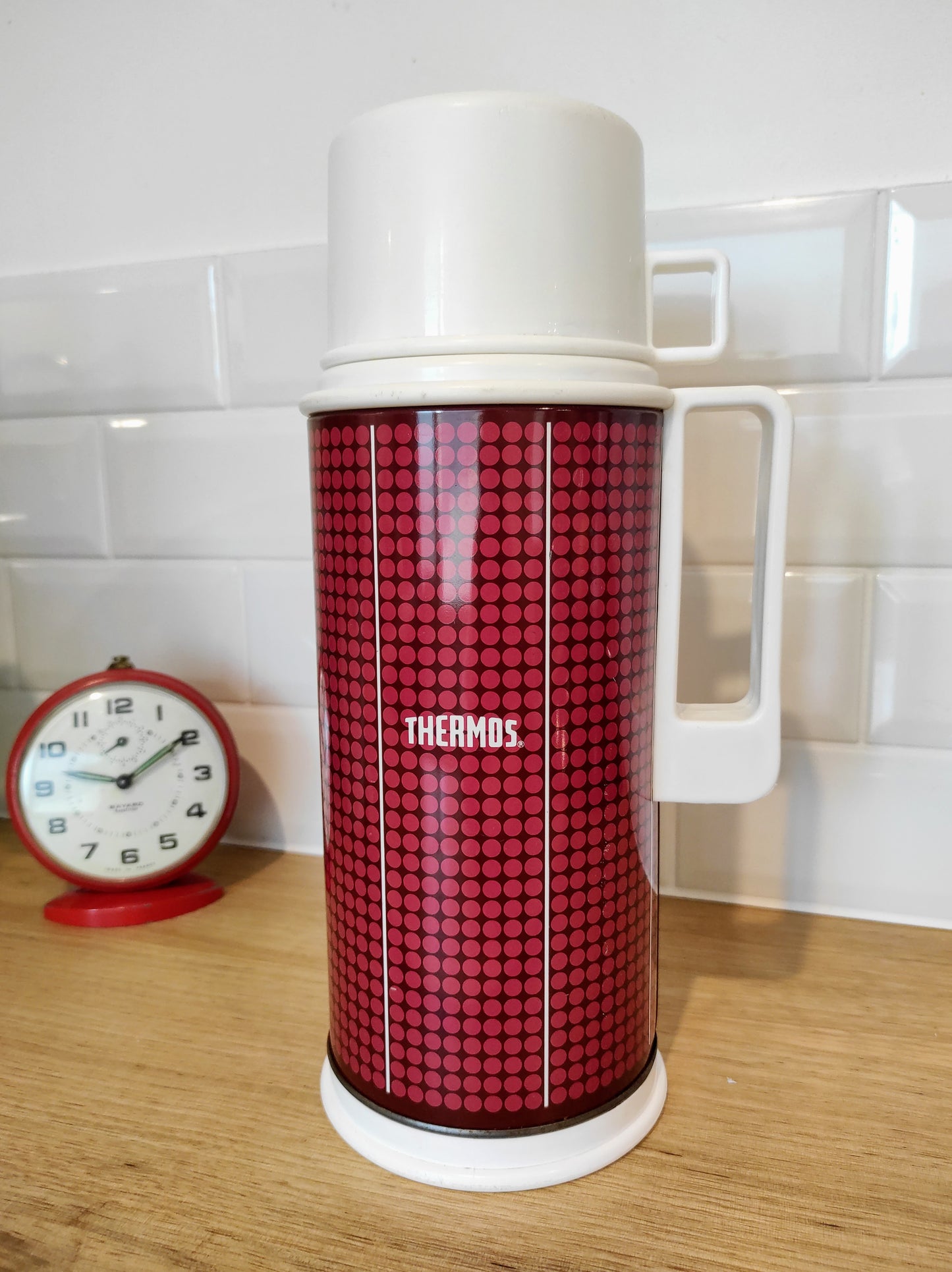 Bouteille isotherme THERMOS vintage made in England années 70. Faites vous remarquer en emportant votre café dans ce superbe thermos à pois des années 70 !  Bouteille isotherme chaud-froid de la célèbre marque THERMOS.  Corps en métal rouge foncé avec des petits pois rouges clairs.  Bouchon et gobelet/tasse en plastique.  Contenance 1 L.