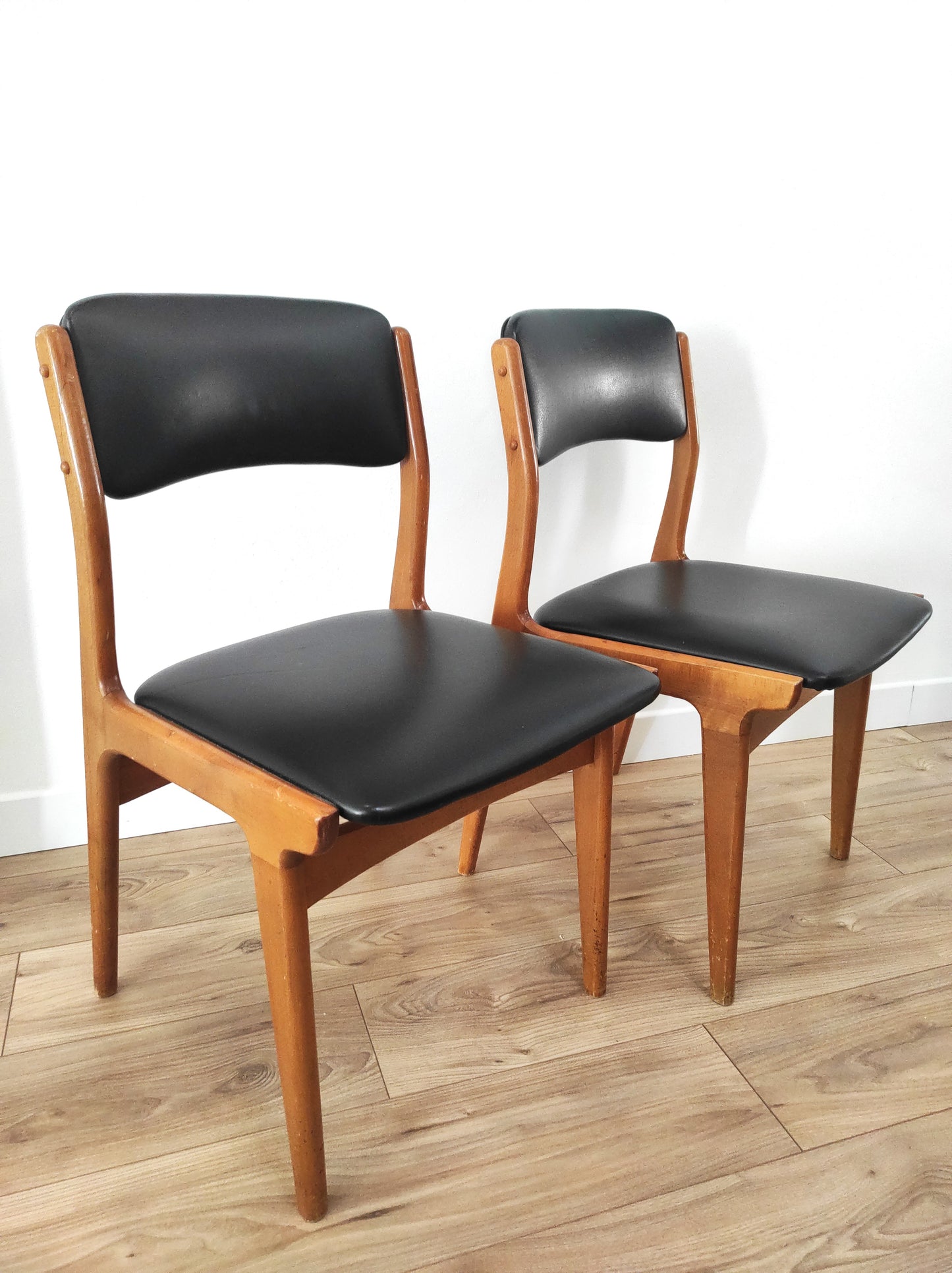 Paire de chaises vintage bois et skaï noir style scandinave estampillées CTC. On aime le look sobre de cette jolie paire de chaises scandinaves en bois et skaï noir.   Estampillées C.T. 3010, elles sont totalement dans leur jus depuis les années 60.   L'assise, le rembourrage et le dessous des chaises sont en très bon état.   A noter : un léger accro sur une assise (voir photo) et quelques marques du temps sur le bois notamment au niveau des pieds mais elles restent en très bon état vu leur âge !