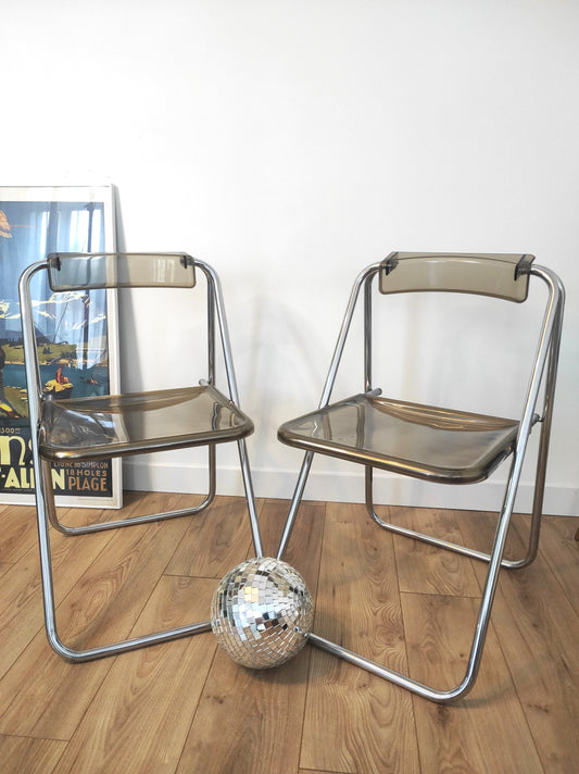 Paire de chaises pliantes vintage plexiglas fumé par Aldo Jacober style PLIA. On aime la simplicité et look très seventies de cette jolie paire de chaises du designer ALDO JACOBER dans le style PLIA GIANCARLO PIRETTI CASTELLI.  Elles sont totalement dans leur jus depuis les années 70.   En plexiglas fumé et métal chromé, peu encombrantes, elles seront parfaites dans votre bureau ou autour de votre table !   Les chaises, pour leur âge sont en très bon état malgré quelques traces du temps.
