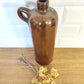 Ancienne bouteille en grès vernissé. Jolie bouteille ancienne en grès vernissé avec anse.  Sa forme élancée est très décorative et accueillera à merveille vos fleurs séchées.   En déco, elle fera aussi faire son effet en accumulation avec d’autres formats ou d'autres couleurs.  A noter : la bouteille ayant était faite artisanalement, elle porte quelques petits défauts qui n'enlèvent rien à son charme. Aucun éclat.