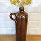 Ancienne bouteille en grès vernissé. Jolie bouteille ancienne en grès vernissé avec anse.  Sa forme élancée est très décorative et accueillera à merveille vos fleurs séchées.   En déco, elle fera aussi faire son effet en accumulation avec d’autres formats ou d'autres couleurs.  A noter : la bouteille ayant était faite artisanalement, elle porte quelques petits défauts qui n'enlèvent rien à son charme. Aucun éclat.
